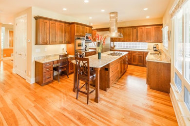 Mid-sized elegant u-shaped light wood floor eat-in kitchen photo in Denver with an undermount sink, shaker cabinets, medium tone wood cabinets, granite countertops, stainless steel appliances and an island