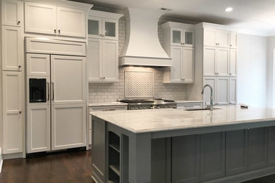 Large transitional single-wall medium tone wood floor eat-in kitchen photo in Other with an undermount sink, raised-panel cabinets, white cabinets, granite countertops, beige backsplash, subway tile backsplash, stainless steel appliances and an island