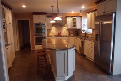 Large traditional l-shaped enclosed kitchen in Grand Rapids with a double-bowl sink, beaded cabinets, white cabinets, granite worktops, beige splashback, stone tiled splashback, stainless steel appliances, ceramic flooring and an island.