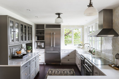 Photo of a traditional grey and white l-shaped kitchen in Austin with a belfast sink, white cabinets, multi-coloured splashback, stainless steel appliances and dark hardwood flooring.