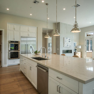 Open concept kitchen ideas - L-shaped medium tone wood floor and brown floor open concept kitchen photo in San Francisco with an undermount sink, shaker cabinets, white cabinets, stainless steel appliances and an island