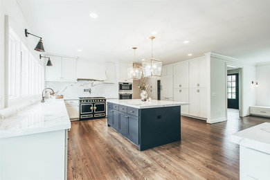 Example of a large transitional u-shaped medium tone wood floor and brown floor eat-in kitchen design in Orange County with a farmhouse sink, shaker cabinets, white cabinets, granite countertops, multicolored backsplash, black appliances, an island and multicolored countertops
