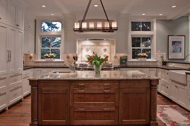 Example of a classic kitchen design in Seattle with a farmhouse sink, shaker cabinets, granite countertops, ceramic backsplash and paneled appliances
