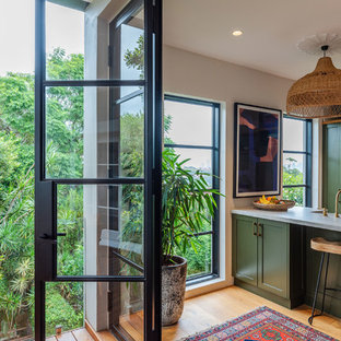Design ideas for a transitional galley kitchen in Sydney with a farmhouse sink, shaker cabinets, green cabinets, stainless steel appliances, medium hardwood floors, a peninsula, brown floor and white benchtop.