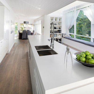 Inspiration for a mid-sized contemporary galley light wood floor and brown floor open concept kitchen remodel in Sydney with flat-panel cabinets, stainless steel appliances, an undermount sink, white cabinets, quartz countertops, white backsplash, glass sheet backsplash and white countertops