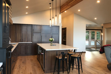 Photo of a large traditional l-shaped open plan kitchen in Seattle with a submerged sink, beaded cabinets, dark wood cabinets, engineered stone countertops, white splashback, ceramic splashback, integrated appliances, light hardwood flooring, an island and white worktops.