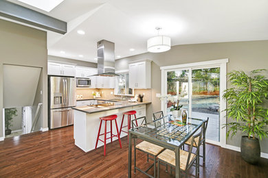 Example of a mid-sized transitional u-shaped medium tone wood floor and brown floor eat-in kitchen design in Seattle with an undermount sink, shaker cabinets, white cabinets, quartz countertops, gray backsplash, glass tile backsplash, stainless steel appliances, a peninsula and gray countertops
