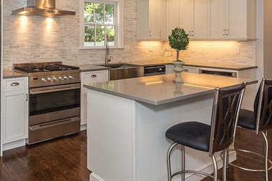 Open concept kitchen - mid-sized contemporary l-shaped dark wood floor and brown floor open concept kitchen idea in Boston with a farmhouse sink, recessed-panel cabinets, white cabinets, quartz countertops, beige backsplash, mosaic tile backsplash, stainless steel appliances and an island