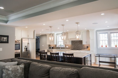 Photo of a large traditional u-shaped open plan kitchen in Boston with a submerged sink, shaker cabinets, white cabinets, quartz worktops, brown splashback, glass tiled splashback, stainless steel appliances, medium hardwood flooring and an island.