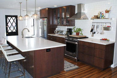 Example of a mid-sized trendy galley medium tone wood floor and brown floor open concept kitchen design in Philadelphia with an undermount sink, glass-front cabinets, dark wood cabinets, quartzite countertops, white backsplash, subway tile backsplash, stainless steel appliances and an island