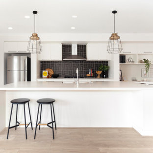 Inspiration for a contemporary galley open plan kitchen in Melbourne with an undermount sink, white cabinets, quartz benchtops, ceramic splashback, stainless steel appliances, laminate floors, with island, beige floor, white benchtop, flat-panel cabinets and black splashback.