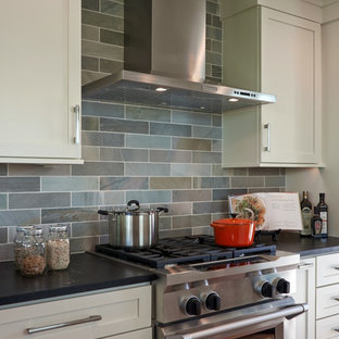 Inspiration for a mid-sized midcentury galley eat-in kitchen in Seattle with shaker cabinets, white cabinets, soapstone benchtops, green splashback, stainless steel appliances, slate splashback, with island and brown floor.