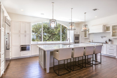 Large transitional u-shaped porcelain tile and brown floor eat-in kitchen photo in Austin with an undermount sink, shaker cabinets, white cabinets, quartz countertops, white backsplash, stainless steel appliances, an island and porcelain backsplash