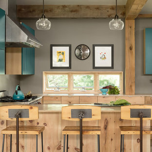 Farmhouse open concept kitchen ideas - Open concept kitchen - country u-shaped open concept kitchen idea in Portland Maine with flat-panel cabinets, turquoise cabinets, stainless steel appliances, a peninsula and beige countertops
