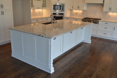 Example of a large arts and crafts l-shaped dark wood floor eat-in kitchen design in Raleigh with shaker cabinets, white cabinets, white backsplash, stainless steel appliances and an island