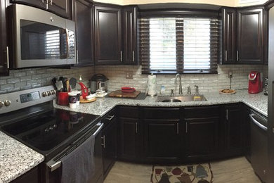 Example of a small trendy u-shaped light wood floor enclosed kitchen design in Philadelphia with an undermount sink, raised-panel cabinets, dark wood cabinets, granite countertops, white backsplash, glass tile backsplash and no island