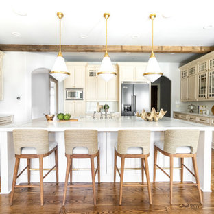 Transitional kitchen pictures - Inspiration for a transitional u-shaped medium tone wood floor, brown floor and exposed beam kitchen remodel in Atlanta with a farmhouse sink, raised-panel cabinets, beige cabinets, multicolored backsplash, stainless steel appliances, an island and multicolored countertops