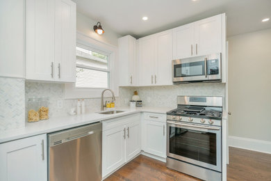 Example of a trendy l-shaped eat-in kitchen design in New York with a single-bowl sink, raised-panel cabinets, white cabinets, marble countertops, gray backsplash, porcelain backsplash, stainless steel appliances and white countertops
