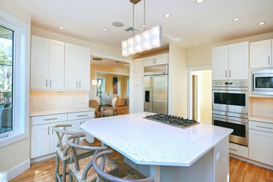 Large trendy u-shaped medium tone wood floor enclosed kitchen photo in Miami with shaker cabinets, white cabinets, quartz countertops, stainless steel appliances and an island
