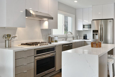 Inredning av ett modernt mellanstort kök, med en undermonterad diskho, släta luckor, vita skåp, marmorbänkskiva, rostfria vitvaror, mellanmörkt trägolv, en köksö och brunt golv