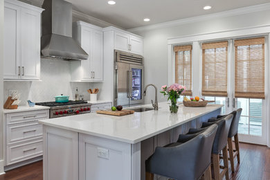 Mid-sized beach style single-wall medium tone wood floor kitchen photo in Orange County with an undermount sink, recessed-panel cabinets, white cabinets, solid surface countertops, white backsplash, ceramic backsplash, stainless steel appliances and an island