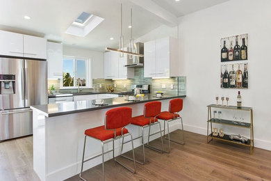 Eat-in kitchen - large contemporary u-shaped medium tone wood floor and brown floor eat-in kitchen idea in San Francisco with an undermount sink, flat-panel cabinets, white cabinets, quartz countertops, green backsplash, matchstick tile backsplash, stainless steel appliances and a peninsula