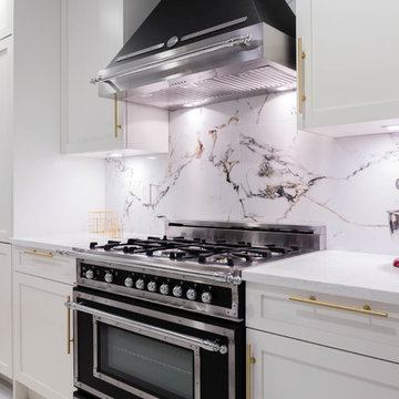 Bertazzoni appliances in a White and gold kitchen with Marble backsplash