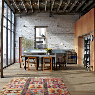 Immagine di una cucina industriale di medie dimensioni con elettrodomestici in acciaio inossidabile, pavimento in legno massello medio e paraspruzzi a effetto metallico