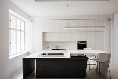 Foto di una grande cucina design con ante lisce, ante bianche, paraspruzzi bianco e pavimento in cemento