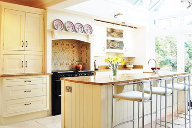 Inspiration for a large traditional single-wall open plan kitchen in Wiltshire with a belfast sink, shaker cabinets, white cabinets, granite worktops, black appliances, ceramic flooring and multiple islands.
