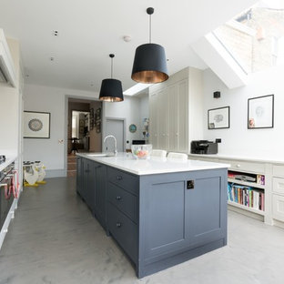 Large classic kitchen in London with shaker cabinets, composite countertops, stainless steel appliances, concrete flooring, an island, grey floors, white worktops, a submerged sink and white cabinets.