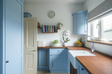 エディンバラにあるラグジュアリーなトラディショナルスタイルのおしゃれなキッチン (シェーカースタイル扉のキャビネット、青いキャビネット、木材カウンター、白いキッチンパネル、アイランドなし) の写真