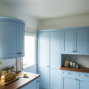 Geschlossene, Zweizeilige, Mittelgroße Klassische Küche ohne Insel mit Landhausspüle, Schrankfronten im Shaker-Stil, blauen Schränken, Arbeitsplatte aus Holz, Küchenrückwand in Weiß, Küchengeräten aus Edelstahl, Travertin und beigem Boden in Edinburgh