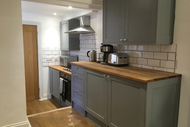 Photo of a contemporary kitchen in Sussex with shaker cabinets, grey cabinets, wood worktops and metro tiled splashback.