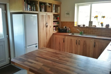 Photo of a large rustic u-shaped open plan kitchen in Other with a double-bowl sink, shaker cabinets, medium wood cabinets, wood worktops, orange splashback, porcelain splashback, laminate floors, a breakfast bar, grey floors and brown worktops.