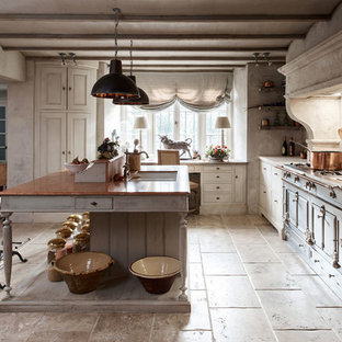 This is an example of a mediterranean l-shaped open plan kitchen in London with limestone benchtops, a double-bowl sink, flat-panel cabinets, white cabinets, white splashback, coloured appliances and with island.