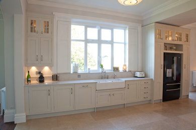 Large traditional u-shaped open plan kitchen in Other with a belfast sink, shaker cabinets, white cabinets, quartz worktops, black appliances, porcelain flooring and a breakfast bar.