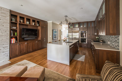 Example of a mid-sized transitional u-shaped medium tone wood floor kitchen pantry design in Chicago with an undermount sink, shaker cabinets, dark wood cabinets, solid surface countertops, gray backsplash, glass tile backsplash, stainless steel appliances and an island