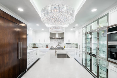 Large minimalist u-shaped dark wood floor, brown floor and tray ceiling eat-in kitchen photo in Dallas with an undermount sink, recessed-panel cabinets, white cabinets, quartz countertops, white backsplash, marble backsplash, stainless steel appliances, an island and white countertops