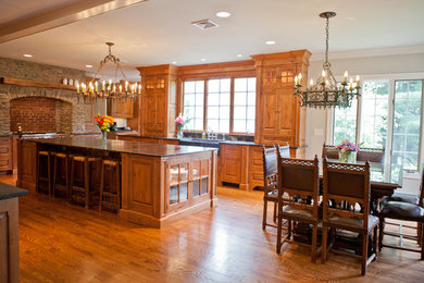 Example of a huge arts and crafts l-shaped medium tone wood floor and brown floor eat-in kitchen design in New York with a farmhouse sink, raised-panel cabinets, distressed cabinets, limestone countertops, brown backsplash, brick backsplash, stainless steel appliances and an island