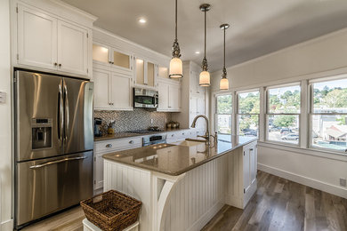 Inspiration for a mid-sized timeless single-wall medium tone wood floor and brown floor kitchen remodel in Bridgeport with a farmhouse sink, beaded inset cabinets, white cabinets, granite countertops, multicolored backsplash, mosaic tile backsplash, stainless steel appliances and an island