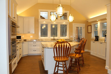 バーリントンにある高級な広いトラディショナルスタイルのおしゃれなキッチン (フラットパネル扉のキャビネット、白いキャビネット、御影石カウンター、シルバーの調理設備) の写真
