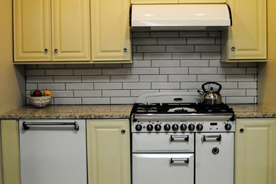 Imagen de cocina clásica de tamaño medio con puertas de armario amarillas, encimera de granito, salpicadero blanco y salpicadero de azulejos de cerámica