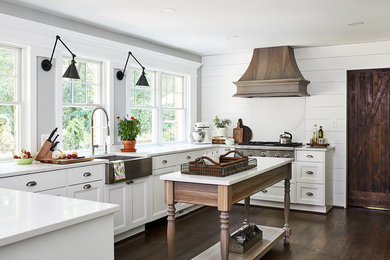 Example of a mid-sized country u-shaped dark wood floor and brown floor eat-in kitchen design in DC Metro with white backsplash, stainless steel appliances, an island, white countertops, a farmhouse sink, recessed-panel cabinets and white cabinets