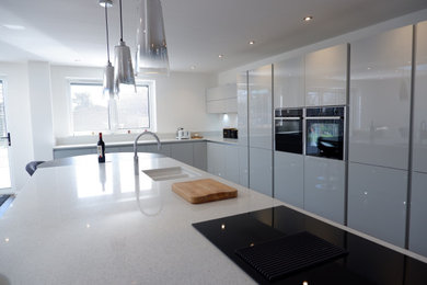 Design ideas for a large modern l-shaped open plan kitchen in Other with a built-in sink, grey cabinets, quartz worktops, black appliances, an island and white worktops.