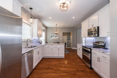 Eat-in kitchen - mid-sized transitional u-shaped dark wood floor and brown floor eat-in kitchen idea in St Louis with an undermount sink, shaker cabinets, white cabinets, granite countertops, gray backsplash, glass tile backsplash, stainless steel appliances and a peninsula