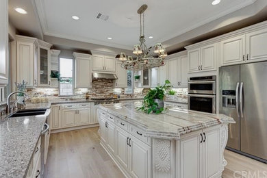 Eat-in kitchen - mid-sized traditional u-shaped medium tone wood floor eat-in kitchen idea in Other with a farmhouse sink, raised-panel cabinets, beige cabinets, granite countertops, multicolored backsplash and an island