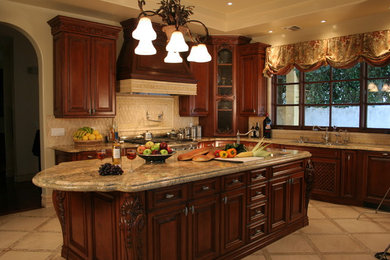 Example of a tuscan kitchen design in Los Angeles with raised-panel cabinets, dark wood cabinets, beige backsplash, stainless steel appliances and granite countertops