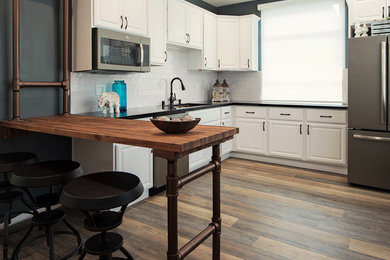 ロサンゼルスにある中くらいなトラディショナルスタイルのおしゃれなキッチン (アンダーカウンターシンク、レイズドパネル扉のキャビネット、白いキャビネット、クオーツストーンカウンター、白いキッチンパネル、サブウェイタイルのキッチンパネル、シルバーの調理設備、無垢フローリング、茶色い床、黒いキッチンカウンター) の写真