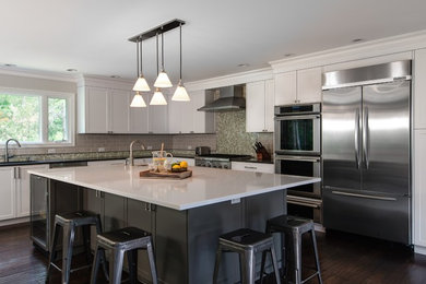 Example of a classic l-shaped dark wood floor kitchen design in Detroit with an undermount sink, shaker cabinets, white cabinets, gray backsplash, subway tile backsplash, stainless steel appliances and an island